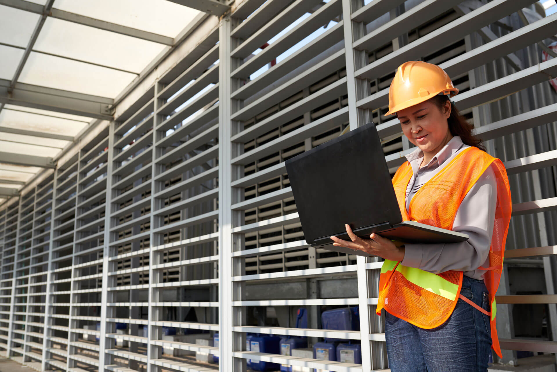 woman looking at laptop with construction safety gear on